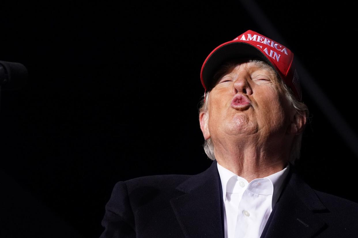 Former President Donald Trump, his lips puckered as if blowing a kiss, appears at a political rally in South Carolina.