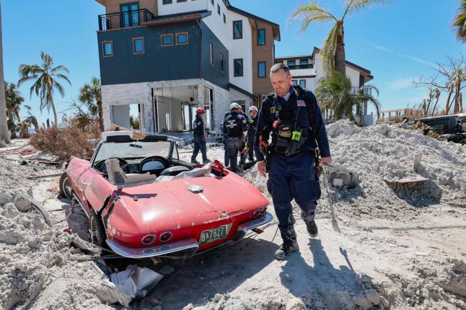 Un miembro del Equipo de Búsqueda y Rescate Urbano Florida Task Force 2 pasa por delante de un Corvette de 1965 dañado por las aguas de la inundación causada por el huracán Ian en Fort Myers Beach el lunes, 3 de octubre de 2022.