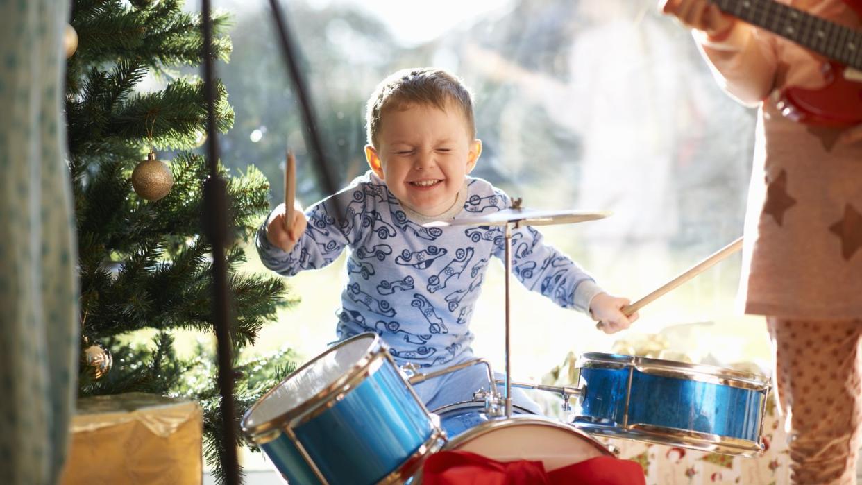 boy and sister playing toy drum kit and guitar on christmas day