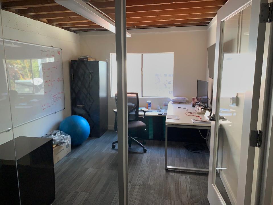 private office with a glass wall, whiteboard, desk, and large window