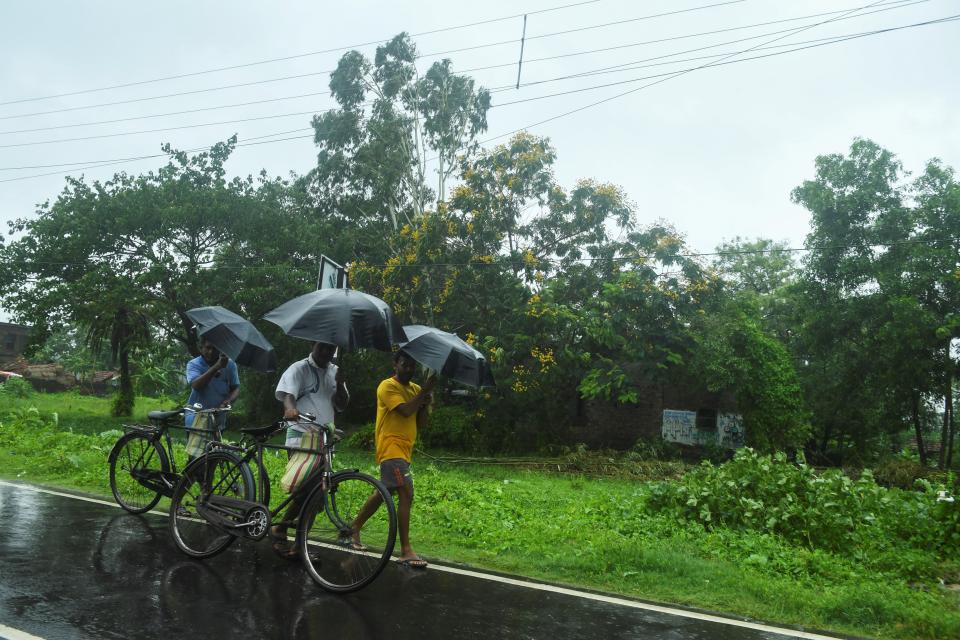 Villagers walk along a road under the rain ahead of the expected landfall of cyclone Amphan in Midnapore, West Bengal, on May 20, 2020. (Photo by DIBYANGSHU SARKAR/AFP via Getty Images)