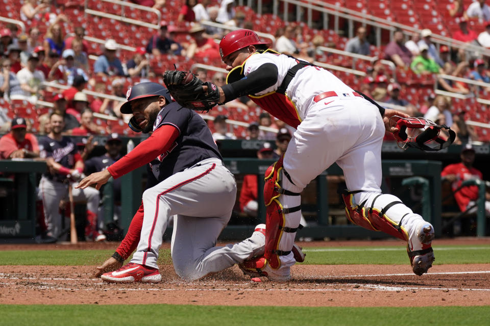 Washington Nationals' Dominic Smith, left, scores past St. Louis Cardinals catcher Willson Contreras during the fifth inning in the first game of a baseball doubleheader Saturday, July 15, 2023, in St. Louis. The contest was the resumption of a game started on Friday, but was suspended due to rain. (AP Photo/Jeff Roberson)