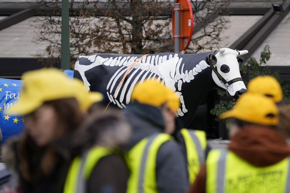 French and Belgian farmers stand in front of a plastic cow with a skeleton painted on it during a demonstration outside the European Parliament in Brussels, Wednesday, Jan. 24, 2024. (AP Photo/Virginia Mayo)