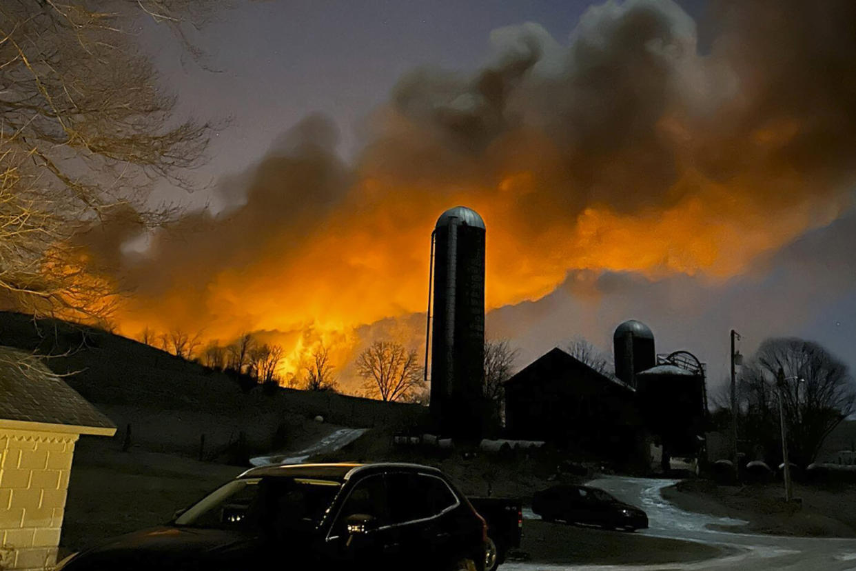 In this photo provided by Melissa Smith, a train fire is seen from her farm in East Palestine, Ohio, Friday, Feb. 3, 2023. A train derailment and resulting large fire prompted an evacuation order in the Ohio village near the Pennsylvania state line on Friday night, covering the area in billows of smoke lit orange by the flames below. (Melissa Smith via AP)