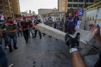 Anti-government protesters remove a concrete wall that was installed by security forces to prevent them from reaching the government palace in Beirut, Lebanon, Thursday, July 2, 2020. Major retailers in Lebanon announced Thursday they will temporarily close in the face of an increasingly volatile currency market and their inability to set prices while the local currency tumbles before the dollar. (AP Photo/Hassan Ammar)