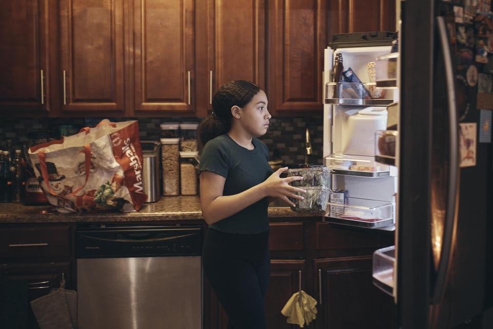 Grace Durham, 11, helps her mother, Elena Romero, not pictured, to put groceries in the refrigerator, Saturday, Jan. 27, 2024, in New York. With the damaging consequences of social media increasingly well documented, many parents are trying to raise their children with restrictions or blanket bans. Teenagers themselves are aware that too much social media is bad for them, and some are initiating social media “cleanses” because of the toll it takes on mental health and grades.(AP Photo/Andres Kudacki)