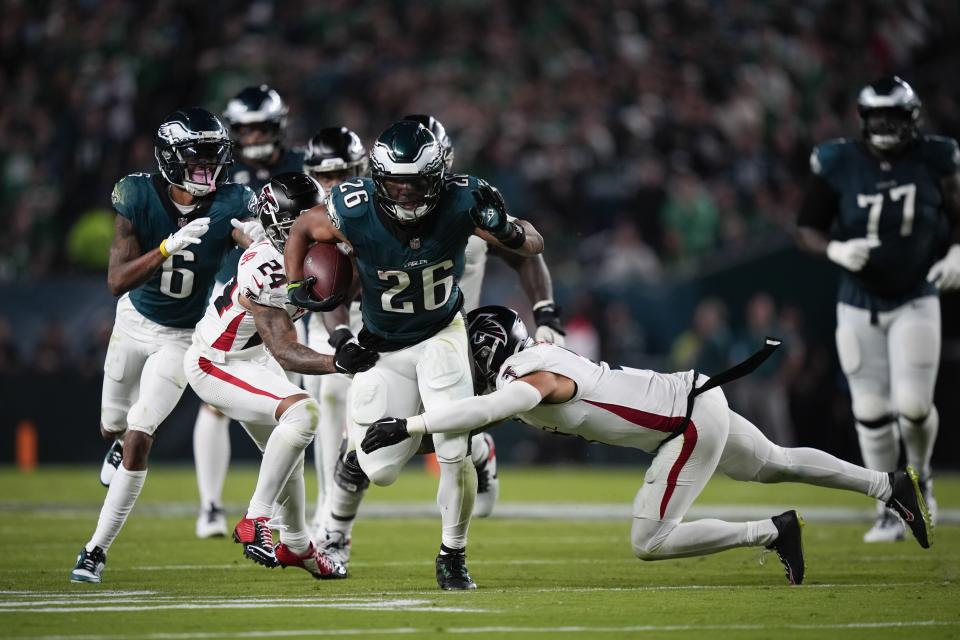 Philadelphia Eagles running back Saquon Barkley (26) runs with the ball under pressure from Atlanta Falcons cornerback A.J. Terrell (24) and Atlanta Falcons safety Jessie Bates III during the second half of an NFL football game on Monday, Sept. 16, 2024, in Philadelphia. (AP Photo/Matt Slocum)