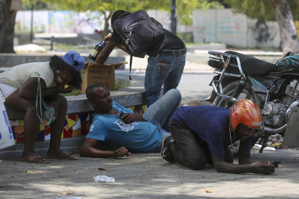 People take cover from gunfire during clashes between police and gangs in the Champs de Mars area next to the National Palace in Port-au-Prince, Haiti, Monday, April 8, 2024. (AP Photo/Odelyn Joseph)