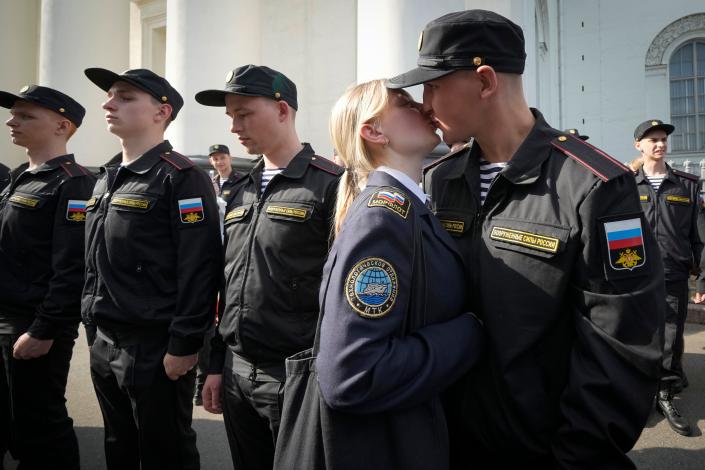 A Russian man kisses his partner while standing next to several other conscripts.