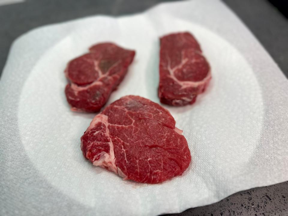 Three slabs of steak on a paper-towel-lined plate.