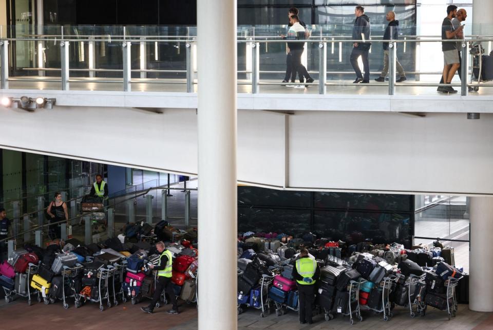 Trabajadores aeroportuarios junto a las colas de equipaje de los pasajeros dispuestas en el exterior de la Terminal 2 del aeropuerto de Heathrow (REUTERS)