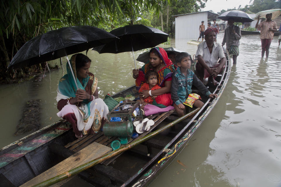 An Indian flood affected family with their belongings on a boat shift to a safer place in Burgaon, east of Gauhati, Assam, India, Monday, July 15, 2019. After causing flooding and landslides in Nepal, three rivers are overflowing in northeastern India and submerging parts of the region, affecting the lives of more than 2 million, officials said Monday. (AP Photo/Anupam Nath)