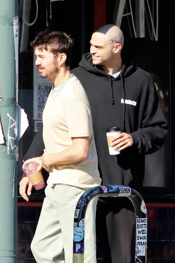 A bald Noah in a sweatshirt and a bear tattoo on the side of his head above his ear