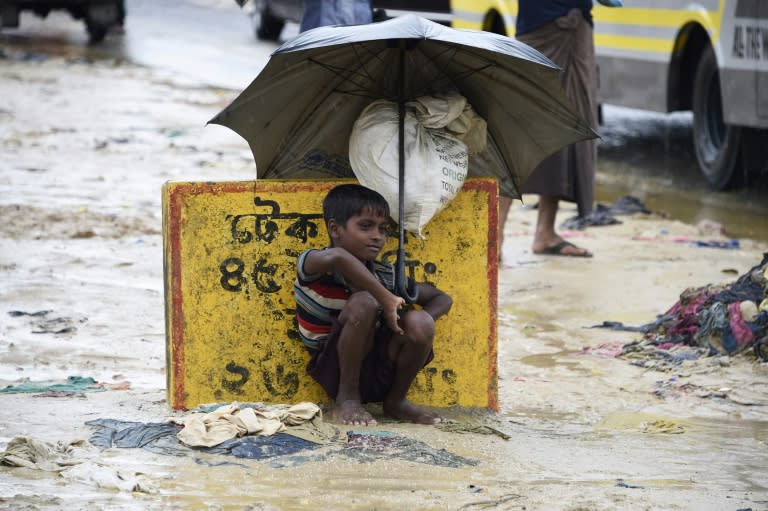 A young Rohingya refugee shelters from the rain with an umbrella while sitting at Kutupalong refugee camp in the Bangladeshi locality of Ukhia on September 19, 2017