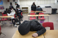 An unidentified student rests on his desk as the Mojave Unified School District Superintendent Katherine Aguirre, center rear, addresses students before their spring break at California City Middle School in California City, Calif., on Friday, March 11, 2022. Since the pandemic started, experts have warned of a mental health crisis facing American children that is now visibly playing out at schools across the country. (AP Photo/Damian Dovarganes)