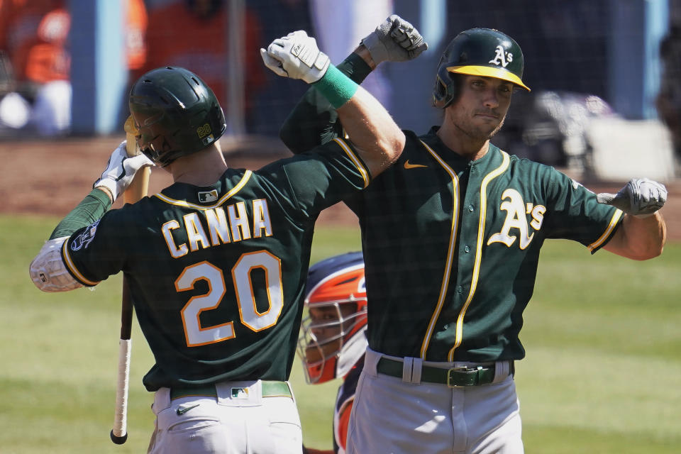 Oakland Athletics' Matt Olson, right, is congratulated by Mark Canha after hitting a solo home run against the Houston Astros during the fourth inning of Game 3 of a baseball American League Division Series in Los Angeles, Wednesday, Oct. 7, 2020. (AP Photo/Marcio Jose Sanchez)