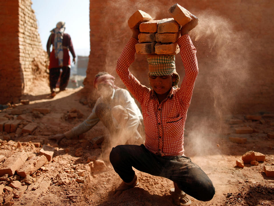 A worker stacks bricks on his head in Lalitpur