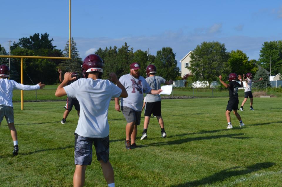 Morenci head coach Nick Wilson walks through his team's stretches prior to starting practice.