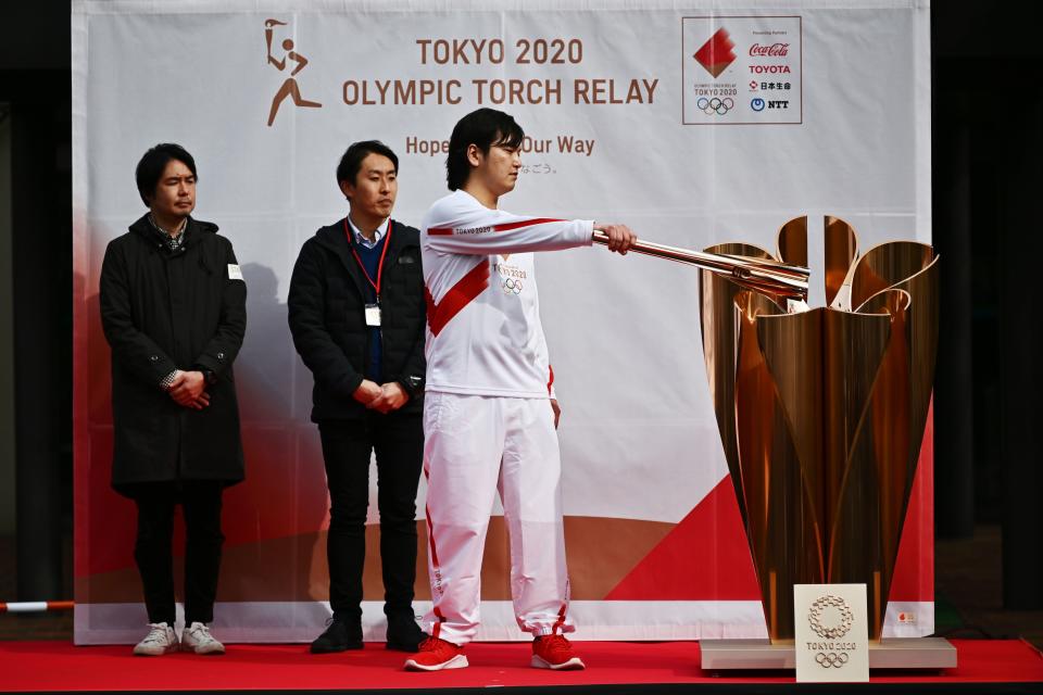 A runner holding an Olympic torch practices lighting a cauldron during a rehearsal of the Tokyo 2020 Olympics torch relay in Tokyo on February 15, 2020. (Photo by CHARLY TRIBALLEAU / AFP) (Photo by CHARLY TRIBALLEAU/AFP via Getty Images)