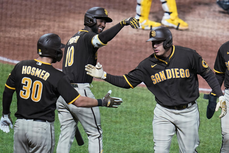 San Diego Padres' Manny Machado, right, celebrates with Eric Hosmer (30) and Jurickson Profar (10) as he returns to the dugout after hitting a two-run home run off Pittsburgh Pirates relief pitcher David Bednar during the eighth inning of a baseball game in Pittsburgh, Saturday, April 30, 2022. (AP Photo/Gene J. Puskar)