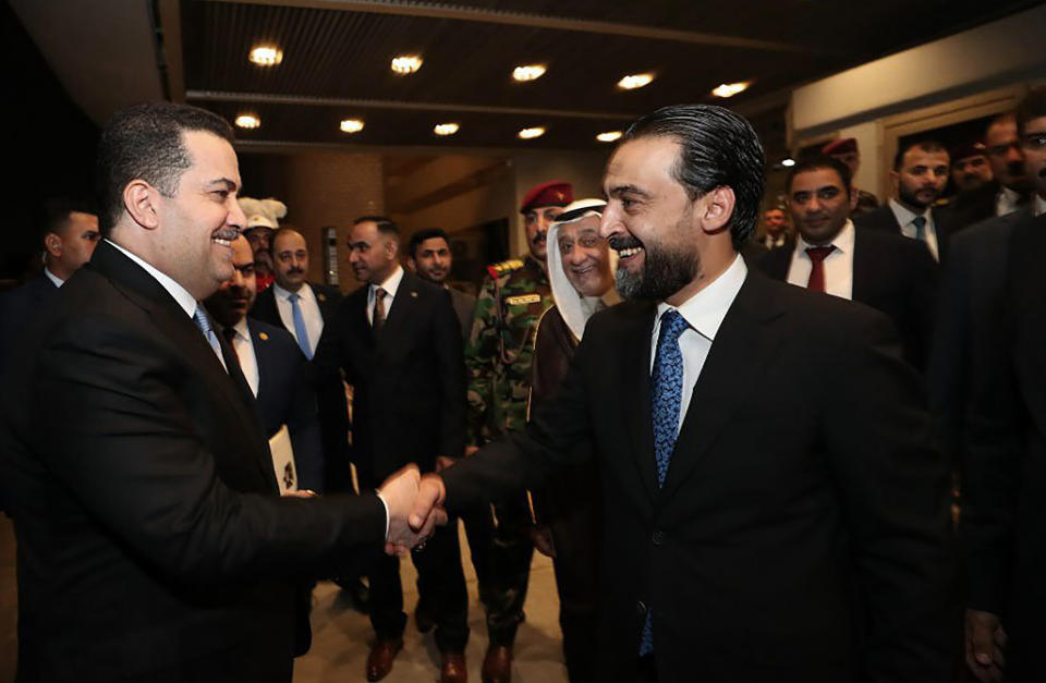 This photo provided by Iraqi Parliament Media Office, Iraq's Parliament Speaker Mohamed al-Halbusi, right, shakes hands with Mohammed Shia al-Sudani, a candidate for Iraq's prime minister position, before the parliament session to approve the new government in Baghdad, Iraq, Thursday, Oct.27, 2022. (Iraqi Parliament Media Office via AP)