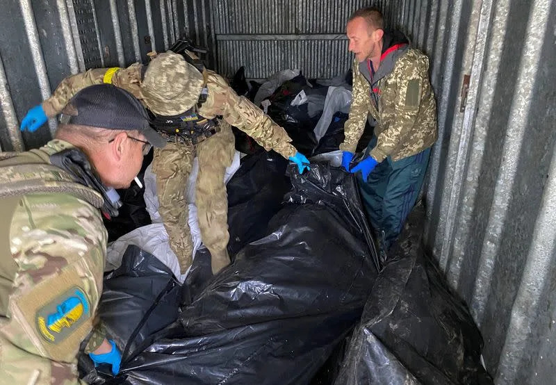 Ukrainian servicemen and a ritual worker load bodies of killed Russian soldiers to a refrigerated rail car, in Kharkiv