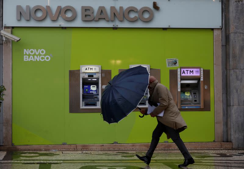 FILE PHOTO: A man walks near ATM machines of a Novo Banco branch in downtown Lisbon