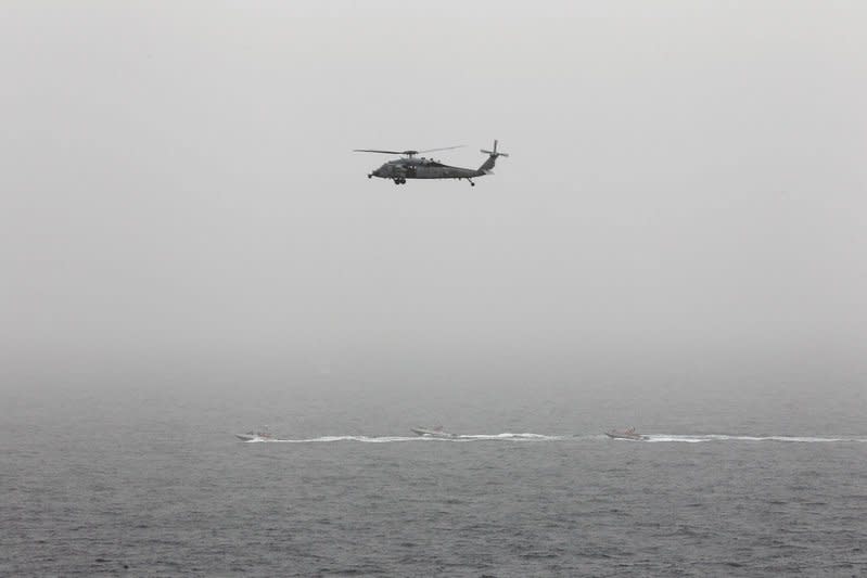 FILE PHOTO - Three Iranian Revolutionary Guard boats are seen near the U.S. aircraft carrier, USS George H. W. Bush while transiting Straits of Hormuz as U.S. Navy helicopter hovers over them during early hours of March 21, 2017. REUTERS/Hamad I Mohammed