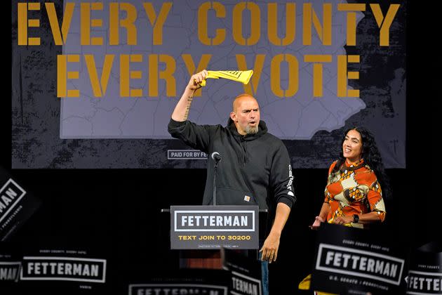 Fetterman greets the crowd as his wife, Gisele Barreto Fetterman, looks on. Gisele delivered introductory remarks that were a hit with the crowd. (Photo: Gene J. Puskar/Associated Press)