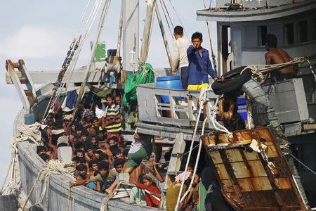 A Myanmar military officer gestures from a boat packed with migrants off Leik Island in the Andaman Sea, May 31, 2015. REUTERS/Soe Zeya Tun