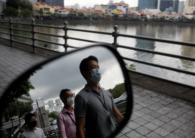 FILE PHOTO: People wearing face masks as a precaution against the coronavirus disease (COVID-19) walk during lunch hour at the central business district in Singapore