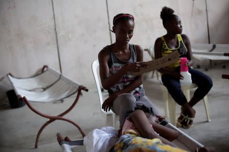 Penina Midi (C) fans her sister who rests on a strecher in the Cholera Treatment Center of Diquini in Port-au-Prince, Haiti, September 7, 2016. REUTERS/Andres Martinez Casares