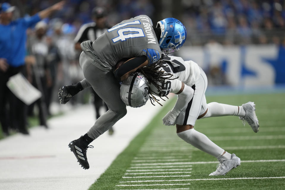 Detroit Lions wide receiver Amon-Ra St. Brown (14) is pushed out of bounds by Las Vegas Raiders safety Tre'von Moehrig (25) during the first half of an NFL football game, Monday, Oct. 30, 2023, in Detroit. (AP Photo/Paul Sancya)