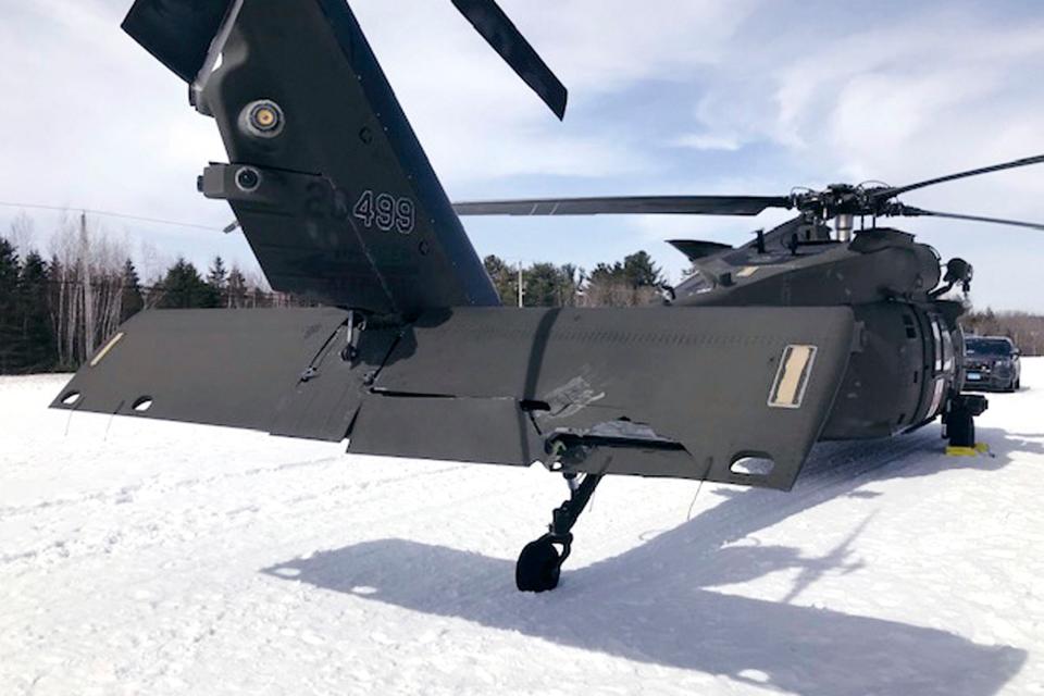 In this U.S. Army photograph by attorney Douglas Desjardins, a damaged Black Hawk helicopter rests on the snow, March 13, 2019, in Worthington, Mass. A Massachusetts man wants the government to pay nearly $10 million after being badly injured in a crash with a Black Hawk helicopter. The lawsuit filed by Jeffrey Smith against the government follows a 2019 crash in which Smith's snowmobile collided with the helicopter that was parked on a trail at dusk. (U.S. Army photograph provided by attorney Douglas Desjardins via AP)