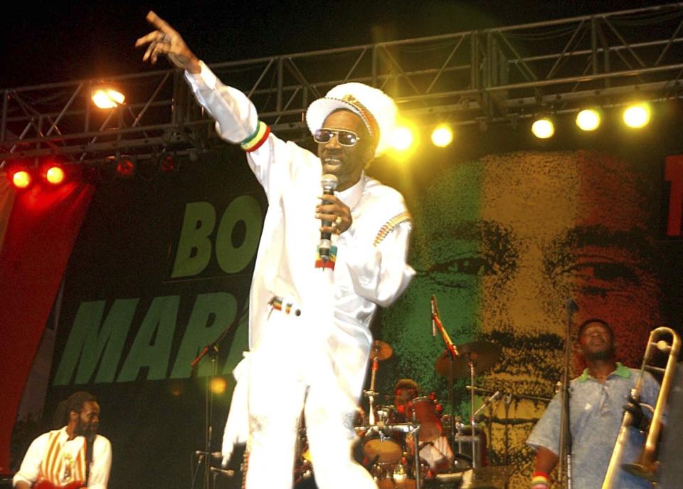 Bunny Wailer performs in front of a backdrop featuring Bob Marley's face