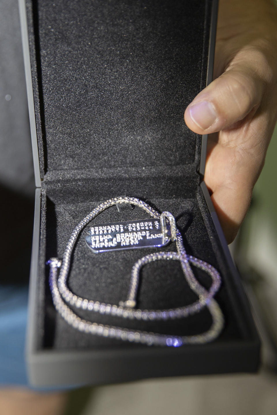 In a photo provided by Mpu Dinani, Aidan Hutchinson carries out a surprise for his mother on NFL football draft day Thursday, April 28, 2022, in Las Vegas, gifting a necklace with a dog tag to honor her grandfather and World War II veteran Joseph Bernardi. He handed Melissa Hutchinson the jewelry before hearing his name called as a Detroit Lions pick. The former Michigan defensive tackle also had a matching necklace and dog tag created for himself. His full name is Aidan Joseph Bernardi Hutchinson with middle names that honor his late great-grandfather, who was part of the World War II jungle fighting unit known as "Merrill's Marauders." (Mpu Dinani via AP)