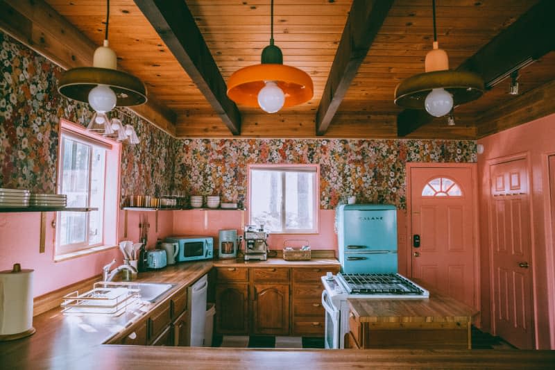 kitchen with peach backsplash and doors, wood ceiling, floral wallpaper, and lots of wood