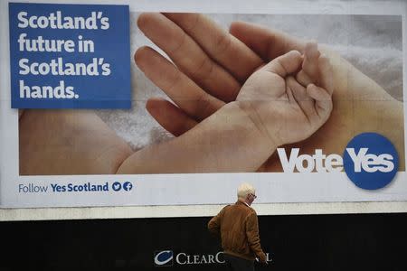 A man walks past a pro-independence poster by the seaside in Aberdeen, northern Scotland September 15, 2014. REUTERS/Dylan Martinez