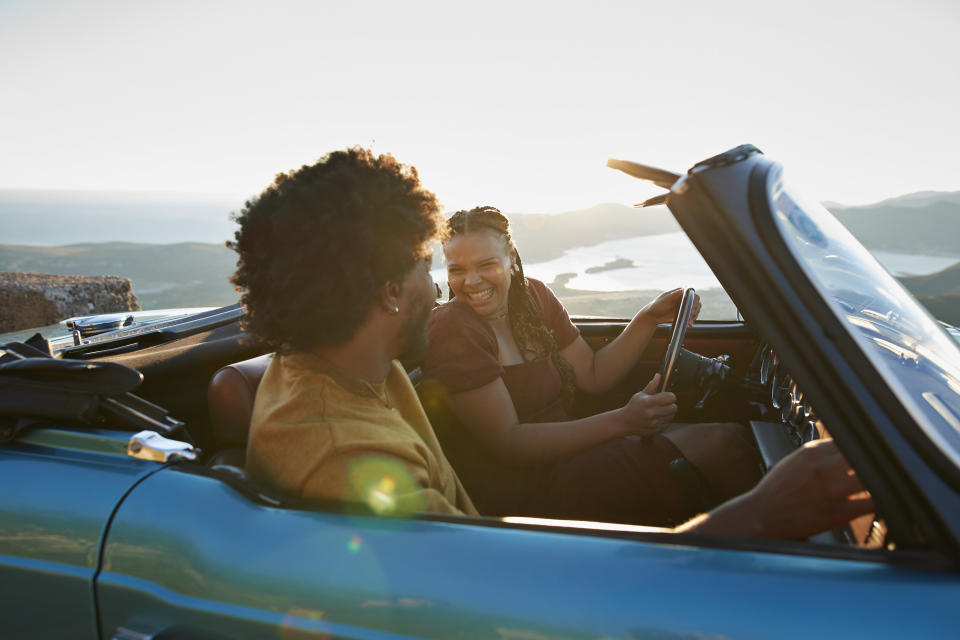 People laughing and driving in a convertible car