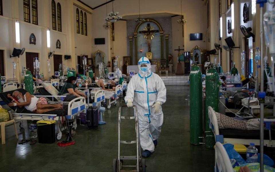 A health worker in full PPE walks out to get an oxygen tank for a Covid-19 patient, in the chapel of Quezon City General Hospital - that has been turned into a coronavirus ward amid rising infections - in Quezon City, Philippines - Eloisa Lopez/Reuters