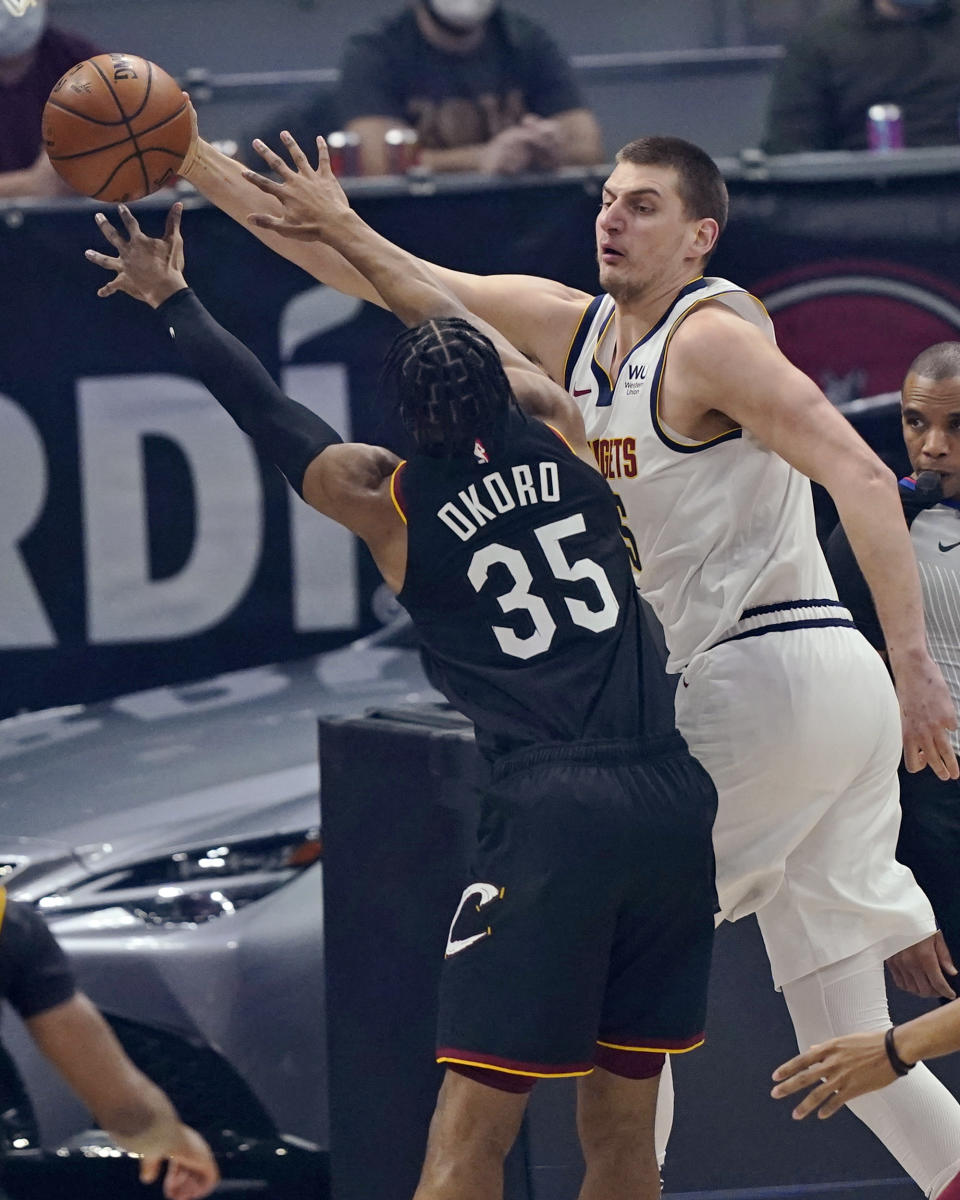 Denver Nuggets' Nikola Jokic, right, passes the ball as Cleveland Cavaliers' Isaac Okoro defends during the first half of an NBA basketball game Friday, Feb. 19, 2021, in Cleveland. (AP Photo/Tony Dejak)