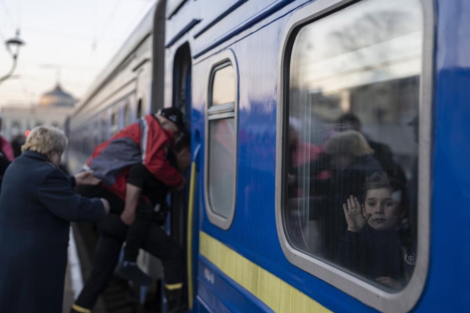 FILE - A child waves through the window of a train as people step on at the train station in Odesa, southern Ukraine, on Wednesday, March 23, 2022. The Black Sea port is mining its beaches and rushing to defend itself from a Mariupol-style fate. Some Western officials believe the city, which is dear to Ukrainians' hearts, could be next. (AP Photo/Petros Giannakouris)