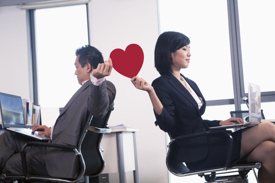 Work romance between two business people holding a heart