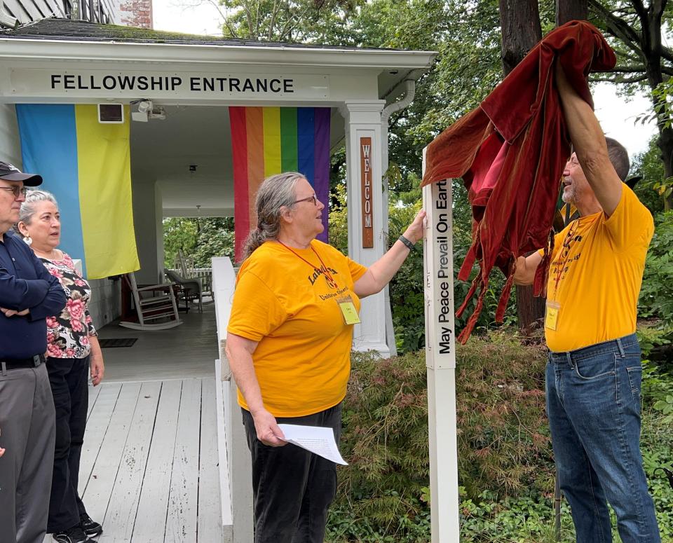 Carol Swift and Richard Nasch, the co-presidents of the fellowship, unveil a peace pole at the anniversary celebration.