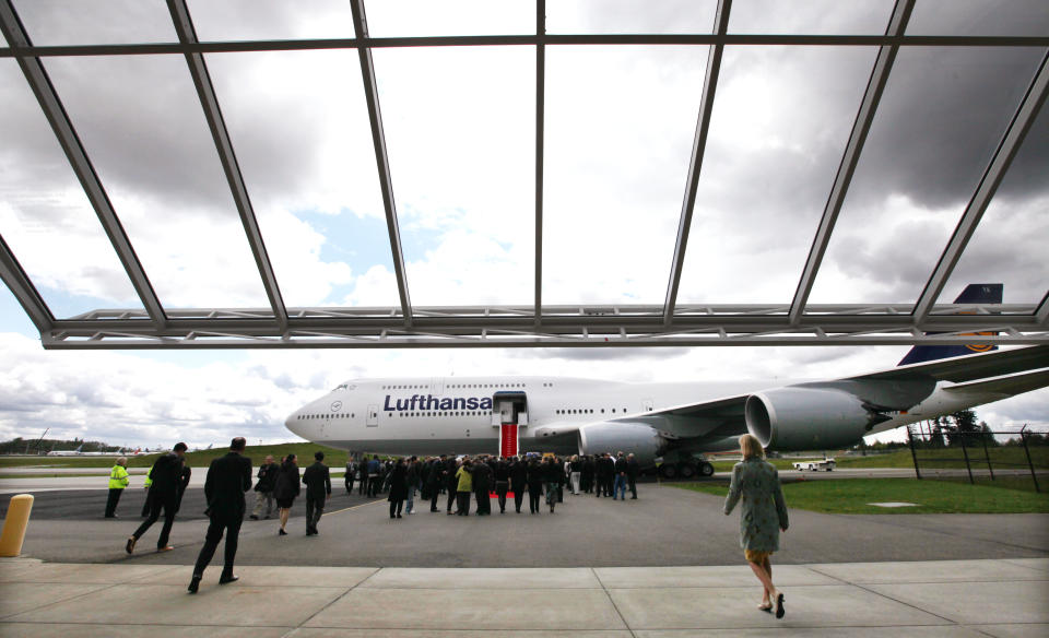 Guests walk toward the first Boeing 747-8 Intercontinental launch jet on the tarmac following remarks inside during a delivery ceremony Tuesday, May 1, 2012, in Everett, Wash. Lufthansa is the launch customer for the Intercontinental and will start service with the airplane between Frankfurt, Germany and Washington, D.C. The 747-8 Intercontinental is a stretched, updated version of the iconic 747 and is expected to bring double-digit improvements in fuel burn and emissions over its predecessor, the 747-400, and generate 30 percent less noise. Boeing delivered the first 747-8 Intercontinental to a private customer in February, more than a year after originally planned. (AP Photo/Elaine Thompson)