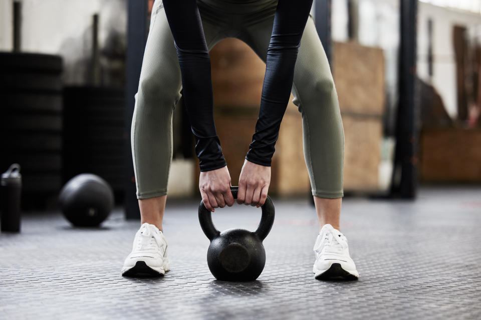 person working out in green tights with a kettlebell in a gym.
