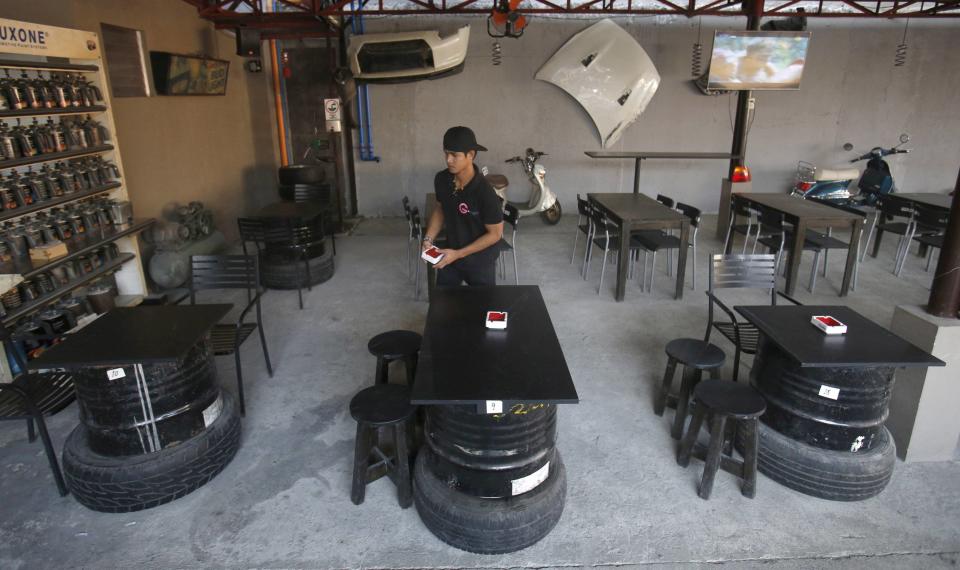 Un camarero camina cerca de las mesas que han sido hechas con los barriles de petróleo en un bar de Paranaque, en Manila (Filipinas).