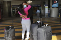 A woman welcomes her husband who just arrived in one of the firsts international flights from the United States due to the coronavirus pandemic, outside the Mariscal Sucre airport, in Quito, Ecuador, Thursday, June 4, 2020. The airport's waiting area was closed to prevent agglomerations amid the COVID-19 pandemic. (AP Photo/Dolores Ochoa)