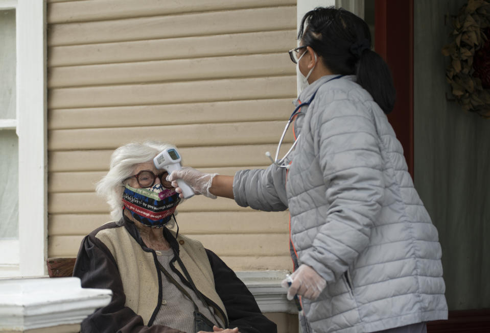 Designer Gere Kavanaugh, left, wears a face mask of her design in the Echo Park neighborhood of Los Angeles, Monday, May 17, 2021. At right, Silver Age Home Health licensed vocational nurse Daisy Cabaluna monitors her temperature during a weekly outdoors visit at her home. California is keeping its rules for wearing face masks in place until the state more broadly lifts its pandemic restrictions on June 15. (AP Photo/Damian Dovarganes)