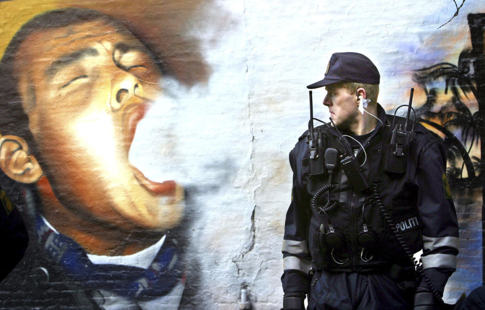 FILE - In this Tuesday, March 16, 2004 file photo, a member of the Copenhagen police patrols the enclave of Christiania in Copenhagen, Denmark. Copenhagen’s mayor is urging urged foreigners not to buy weed in a the city's Christiania neighborhood known for its flourishing hashish trade where a 30-year-old man was killed by shots last month and four people injured. (AP Photo/John McConnico, File)